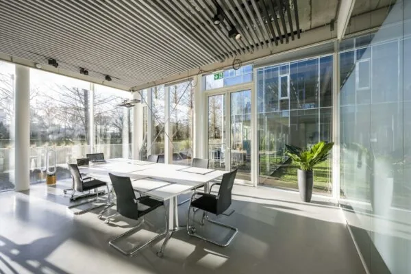 Moderne vergaderruimte aan de Fred. Roeskestraat met veel daglicht, glazen wanden en uitzicht op een groene binnenplaats.